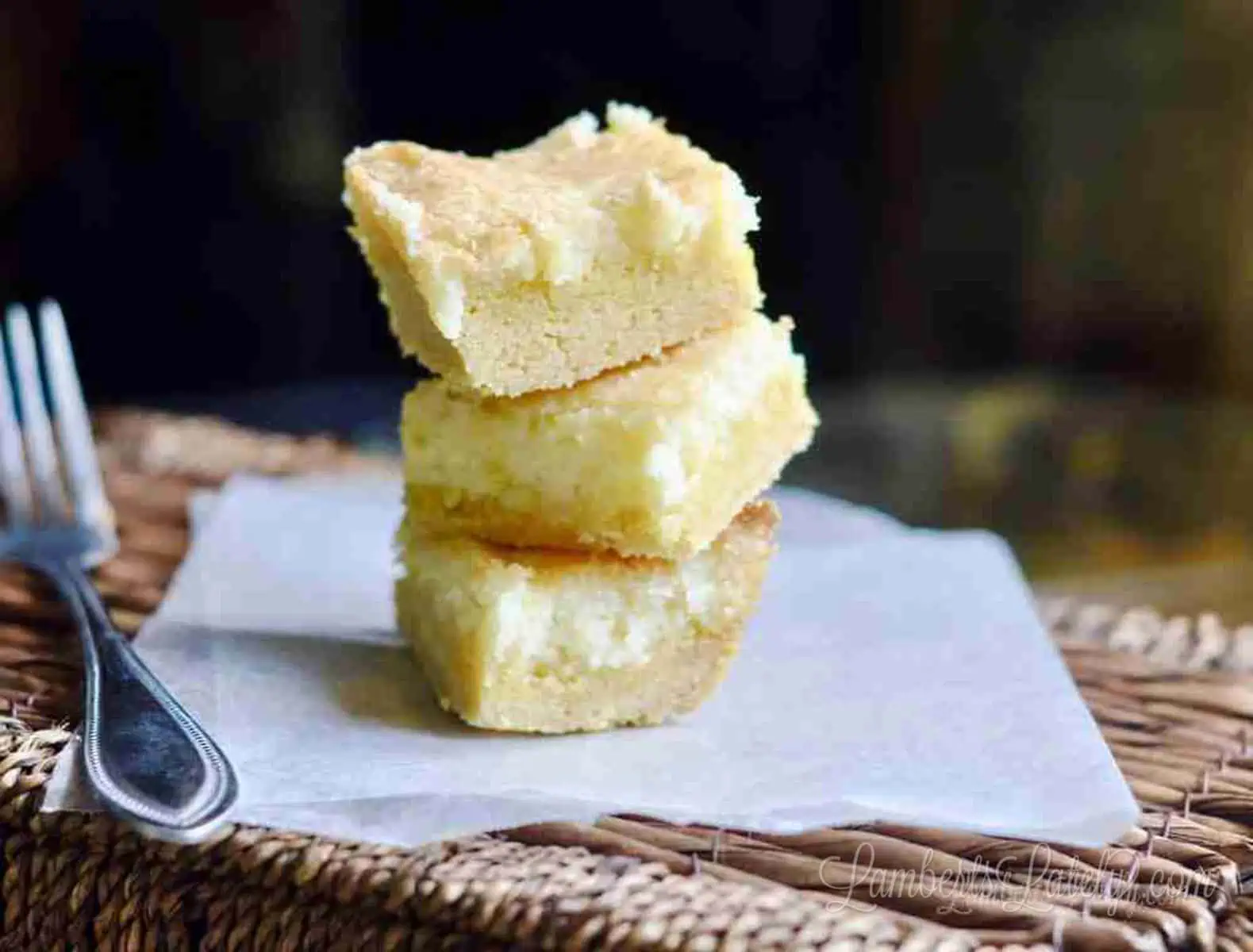 lemon cream cheese bars stacked on a piece of parchment paper.