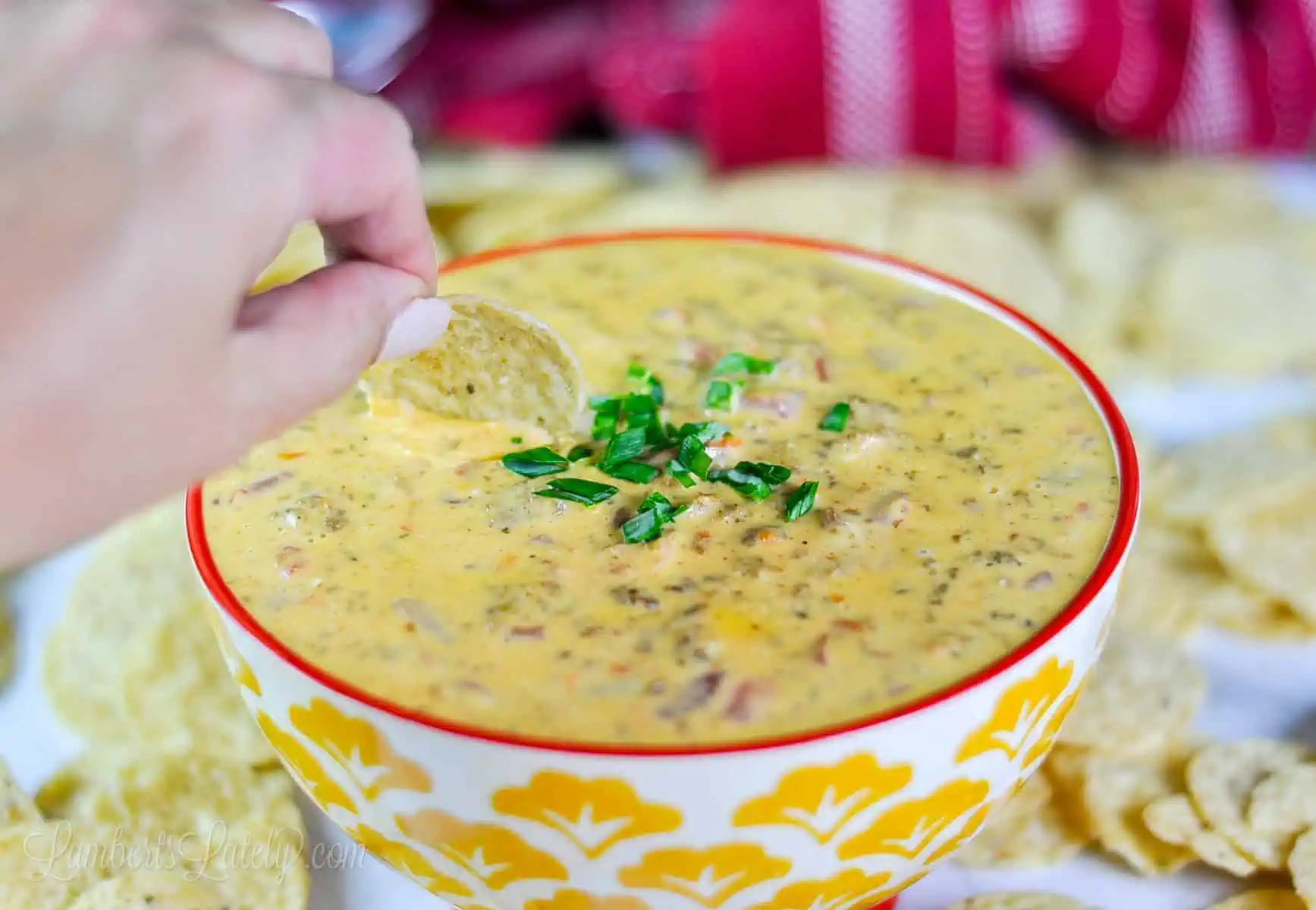 dipping a chip into a bowl of rotel sausage dip.
