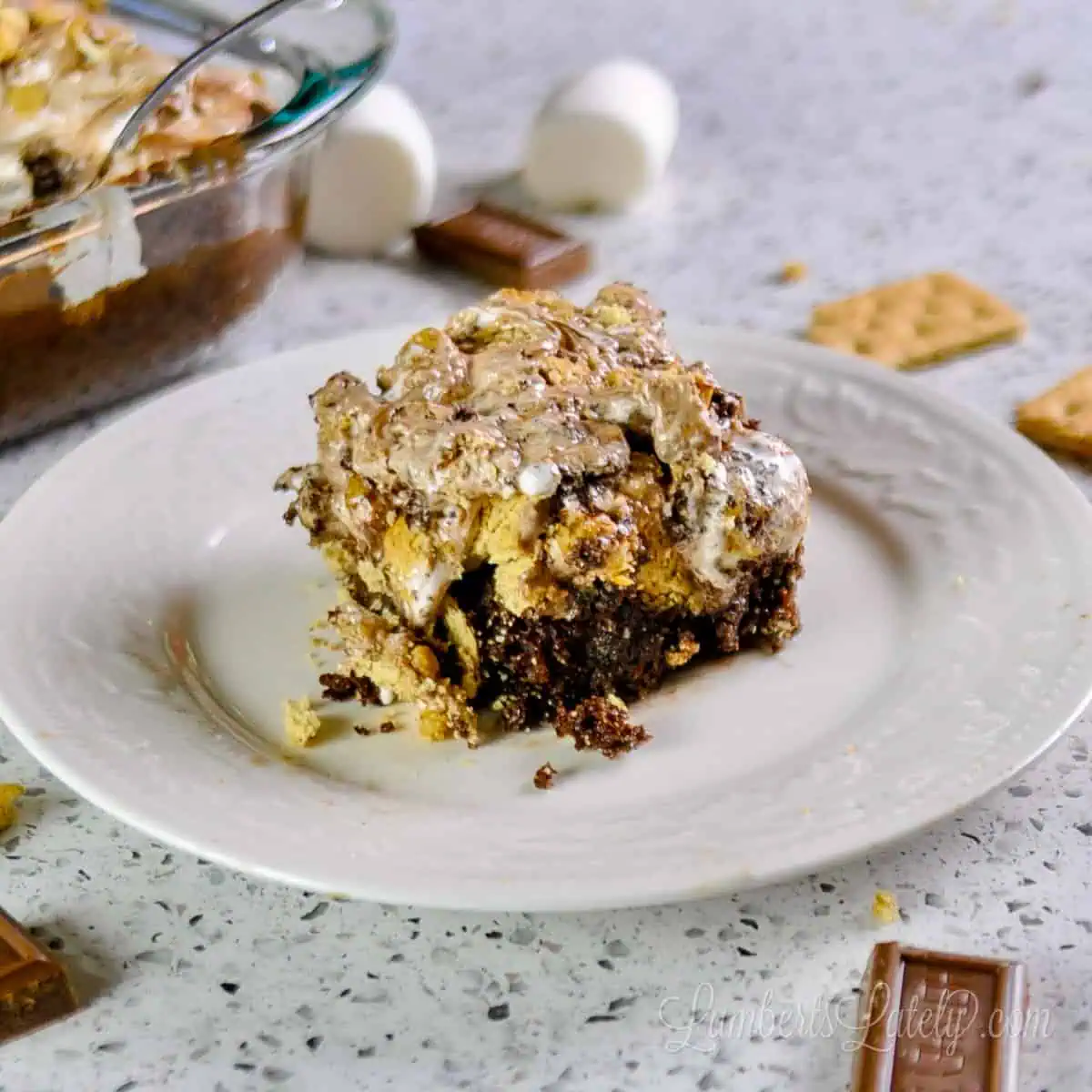 piece of s'mores cake on a plate in front of a baking dish.