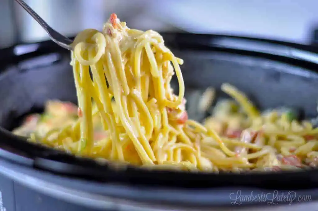 pulling a fork full of chicken spaghetti out of a crock pot.