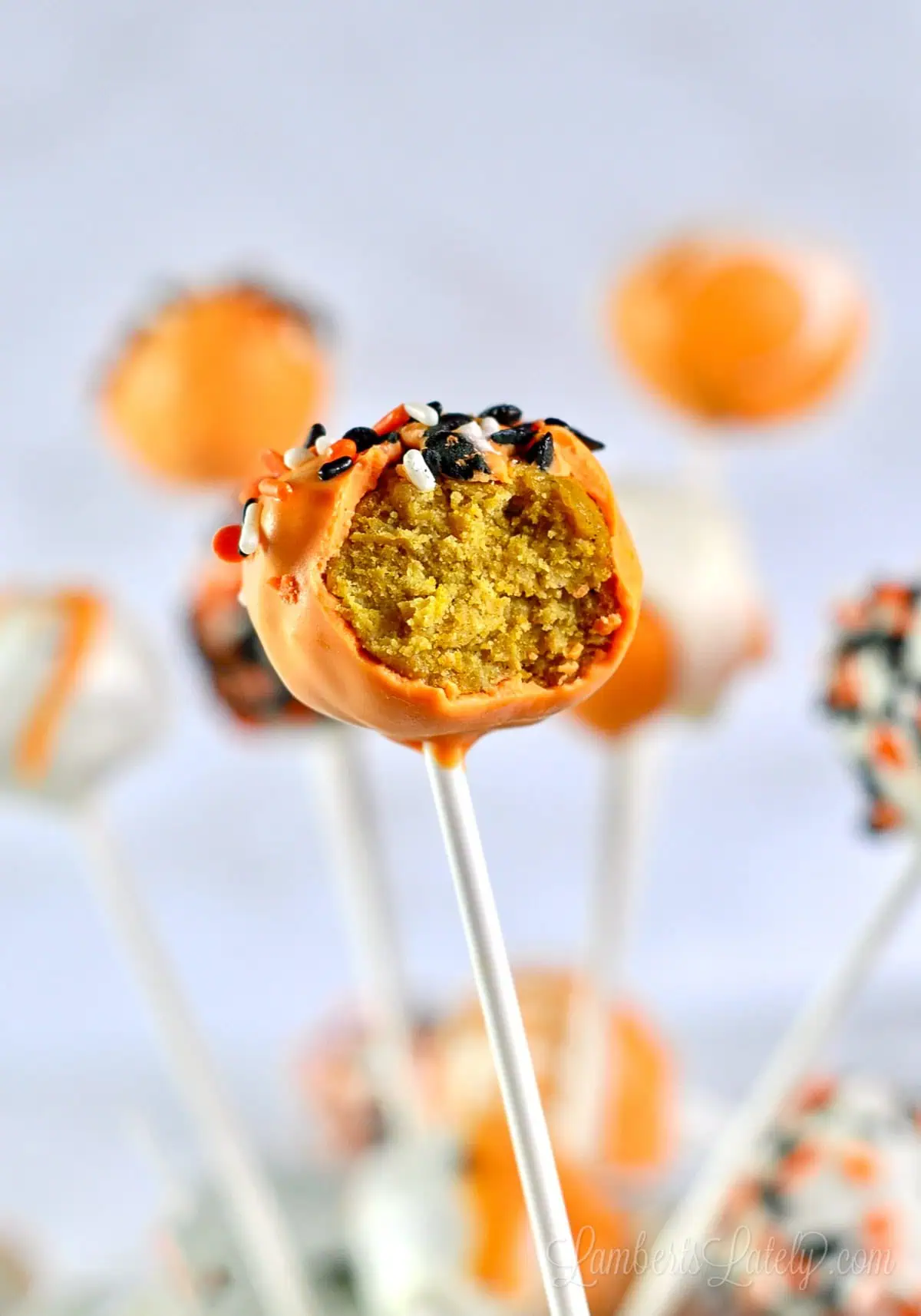 orange pumpkin cake pop missing a bite, showing inside.