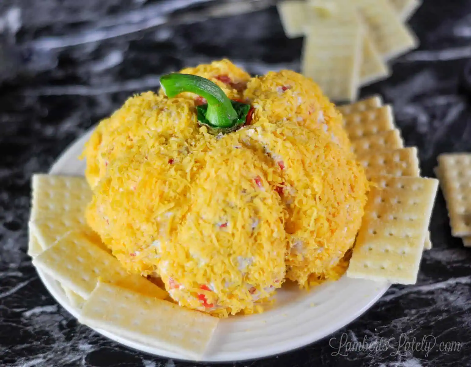 pumpkin cheese ball on a plate surrounded by crackers.