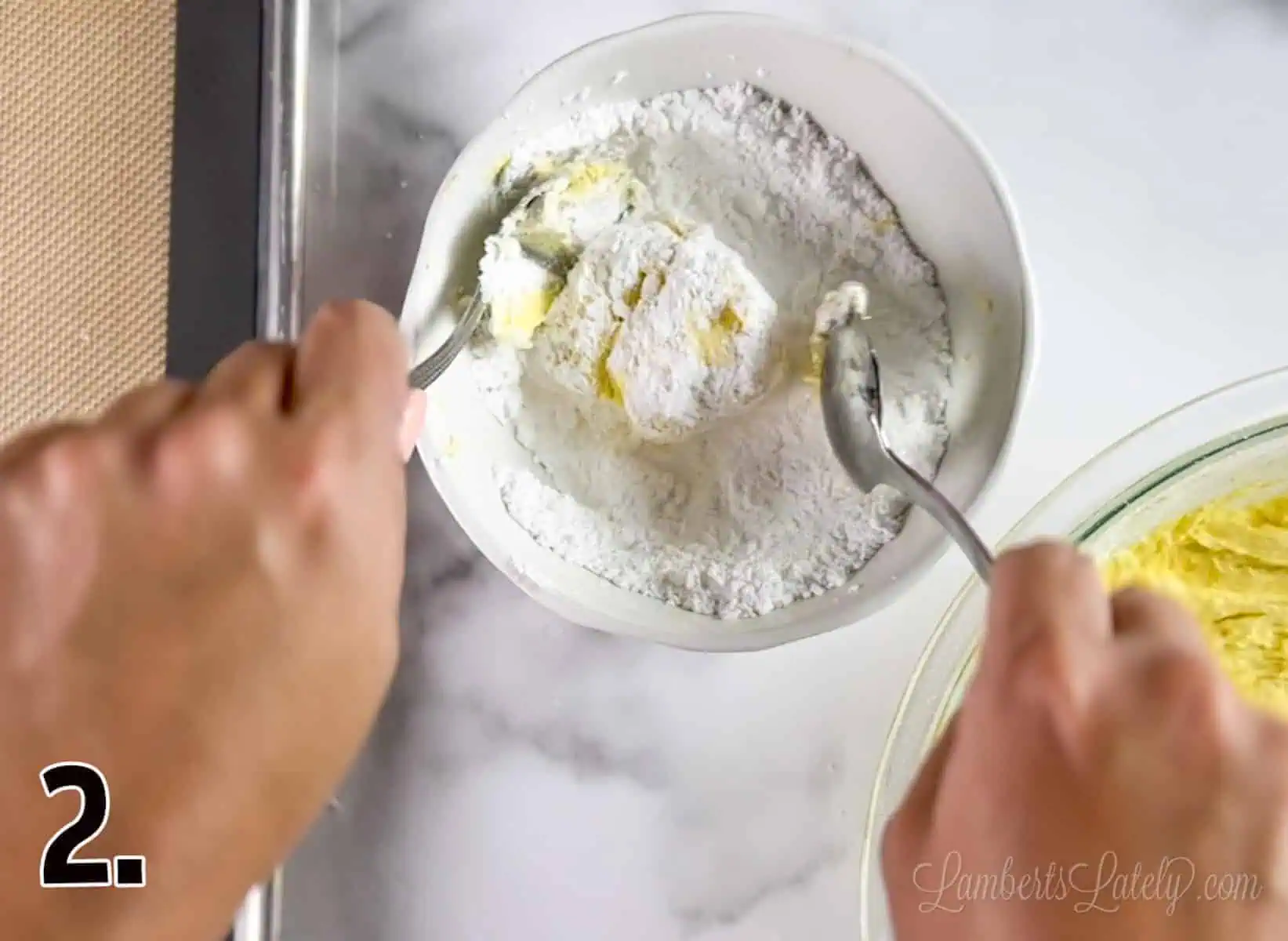 rolling a ball of cookie dough in a bowl of powdered sugar.
