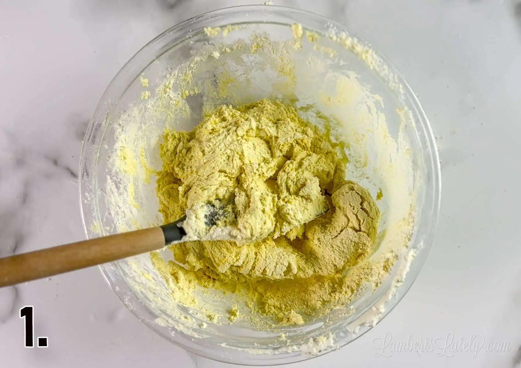 yellow cookie dough in a clear glass bowl.