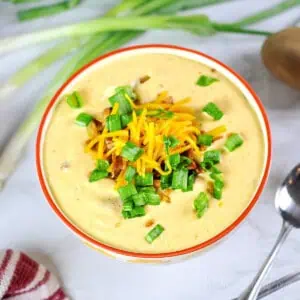 loaded potato soup in a bowl, topped with cheese, green onions, and bacon.