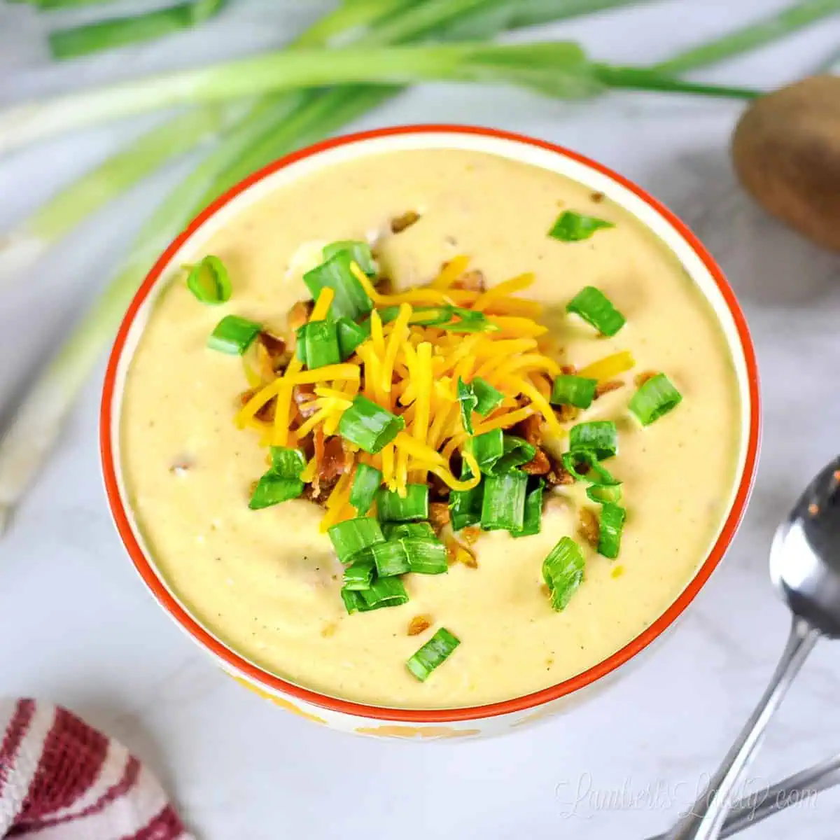 loaded potato soup in a bowl, topped with cheese, green onions, and bacon.