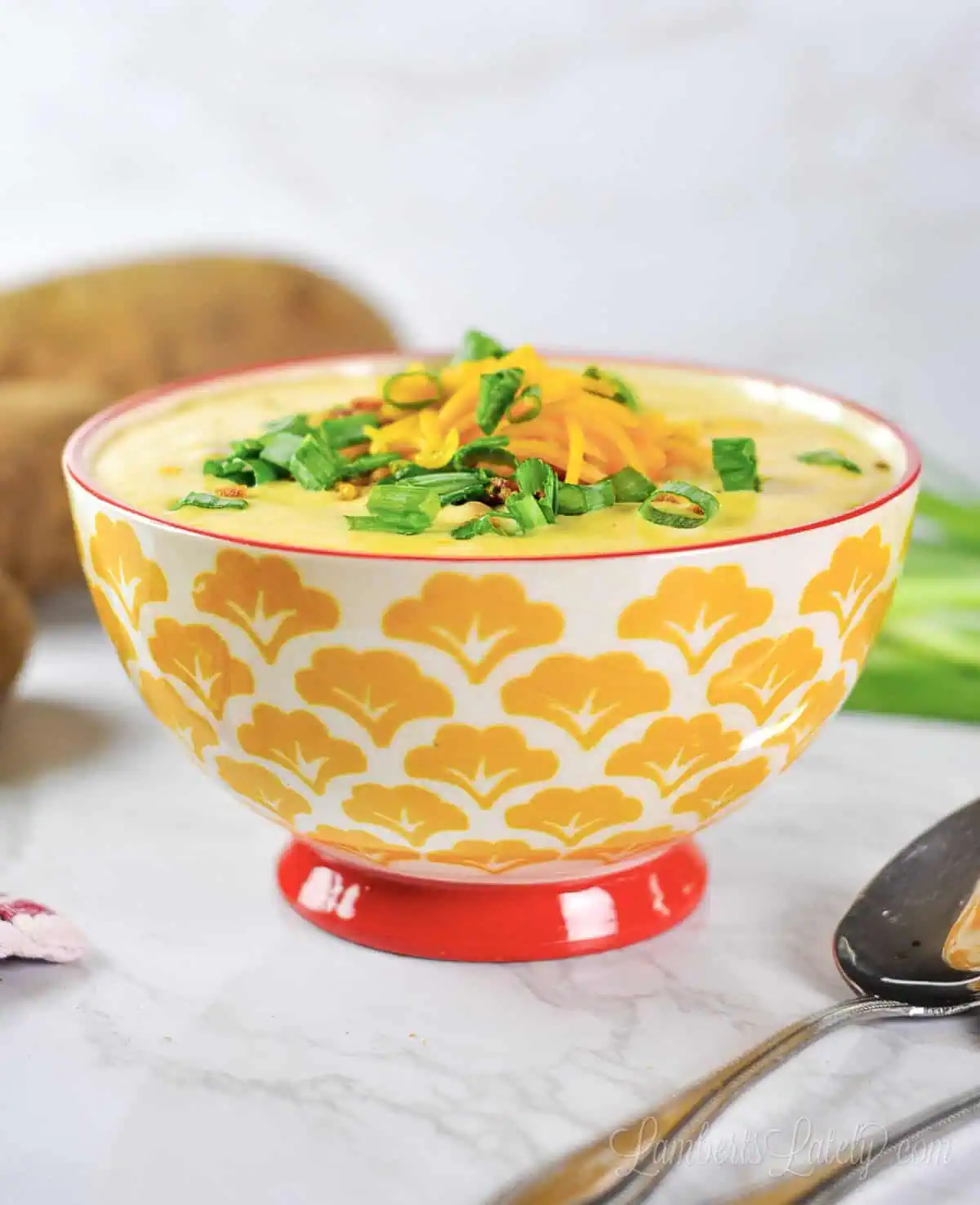loaded potato soup in a bowl, topped with cheese, green onions, and bacon.