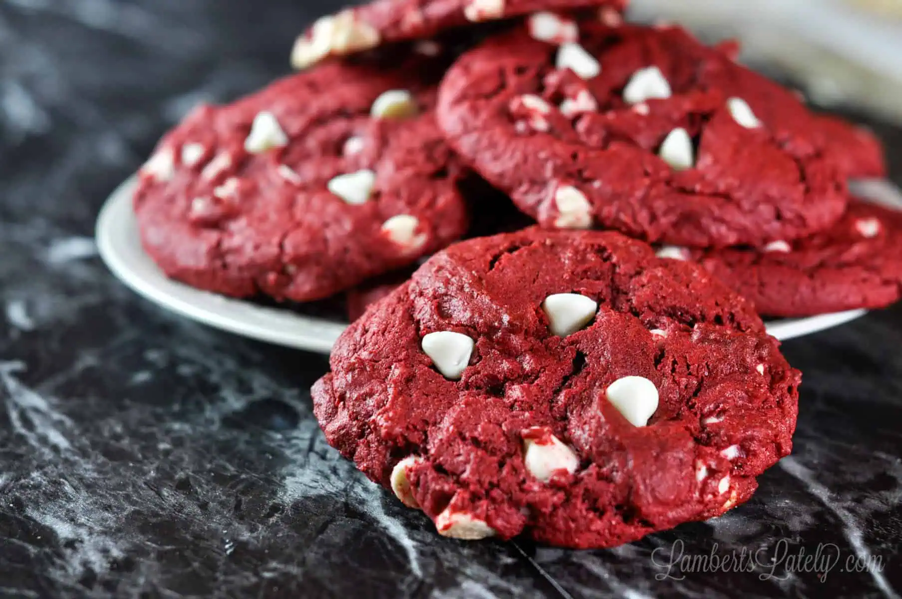 close up of a red velvet cookie next to a plate.