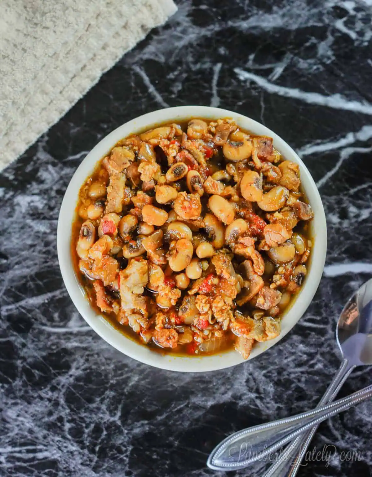 bowl of black eyed peas with a towel and spoons.