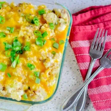 casserole dish of twice baked mashed potatoes, with red kitchen towel and forks.