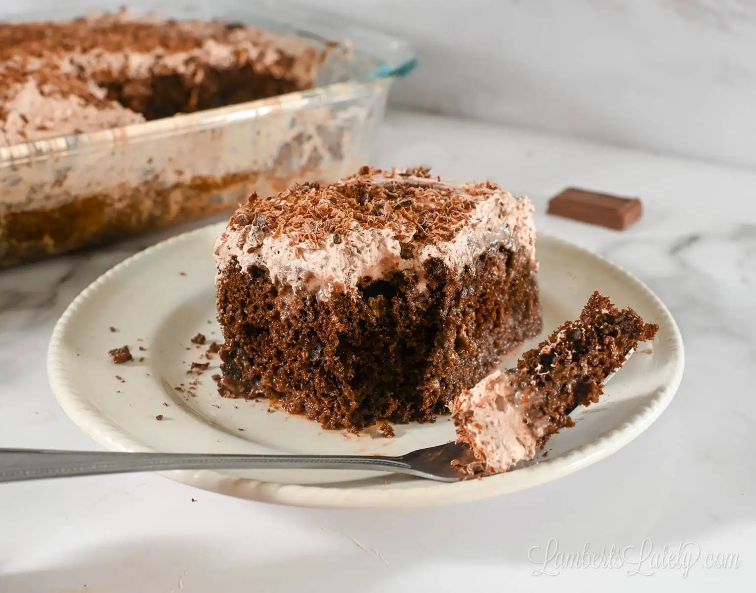 chocolate tres leches cake on a plate with a fork.