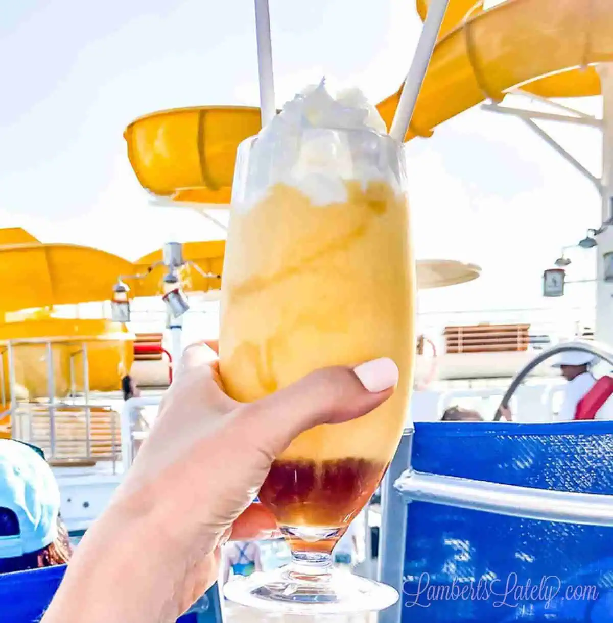 holding a dole whip in front of a slide on a disney cruise ship.