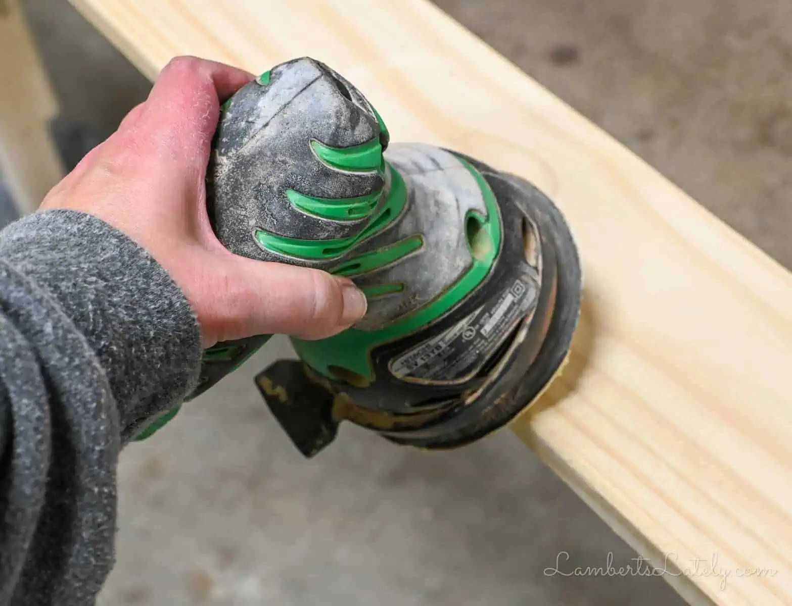 using an orbital sander on the edge of a wood couch table.