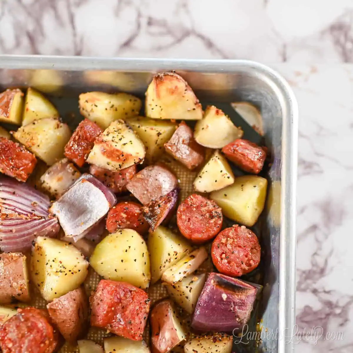 sausage, potatoes, and onion cooked on a sheet pan.