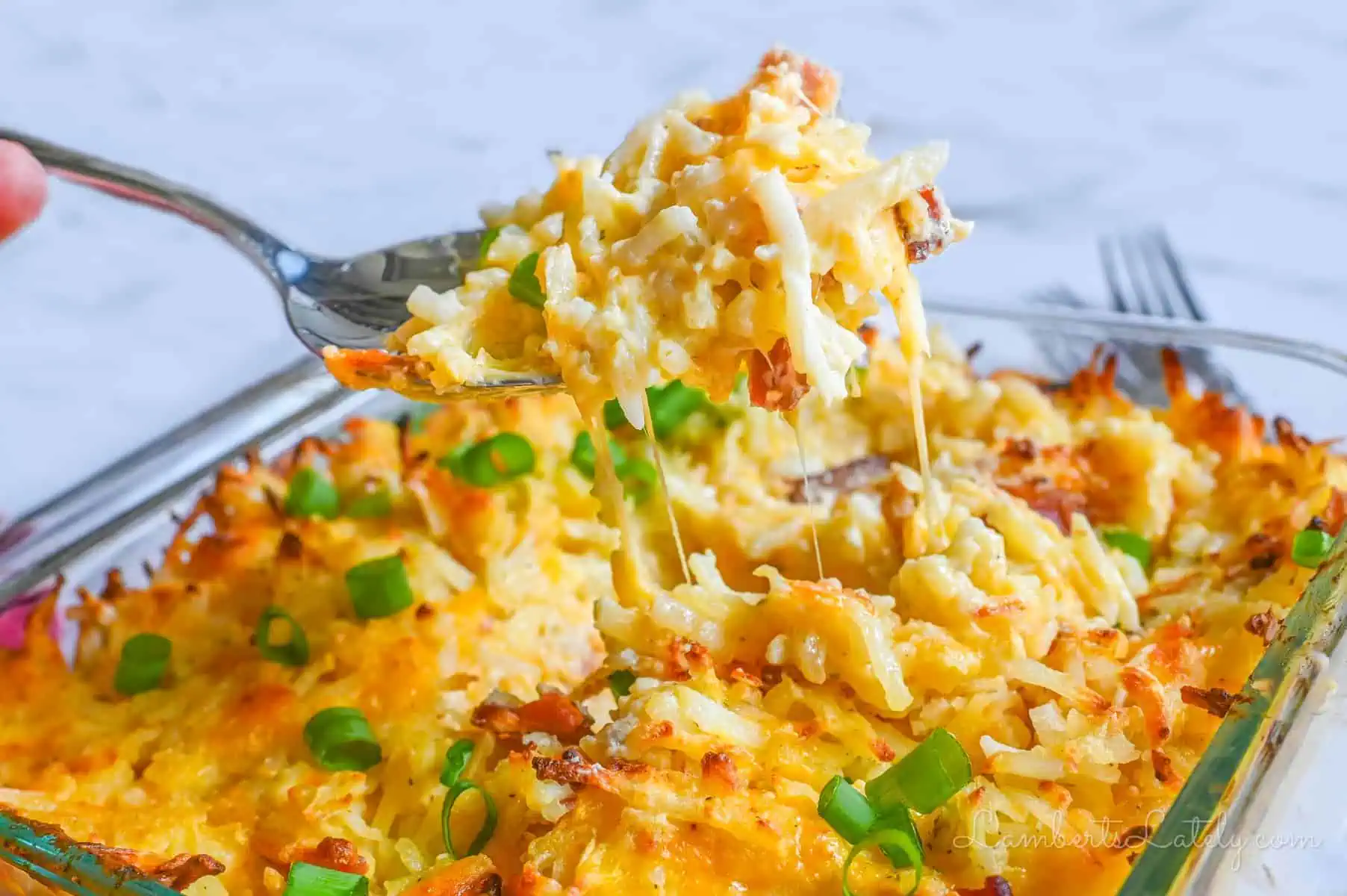 lifting a spoonful of crack potato casserole out of the baking dish.