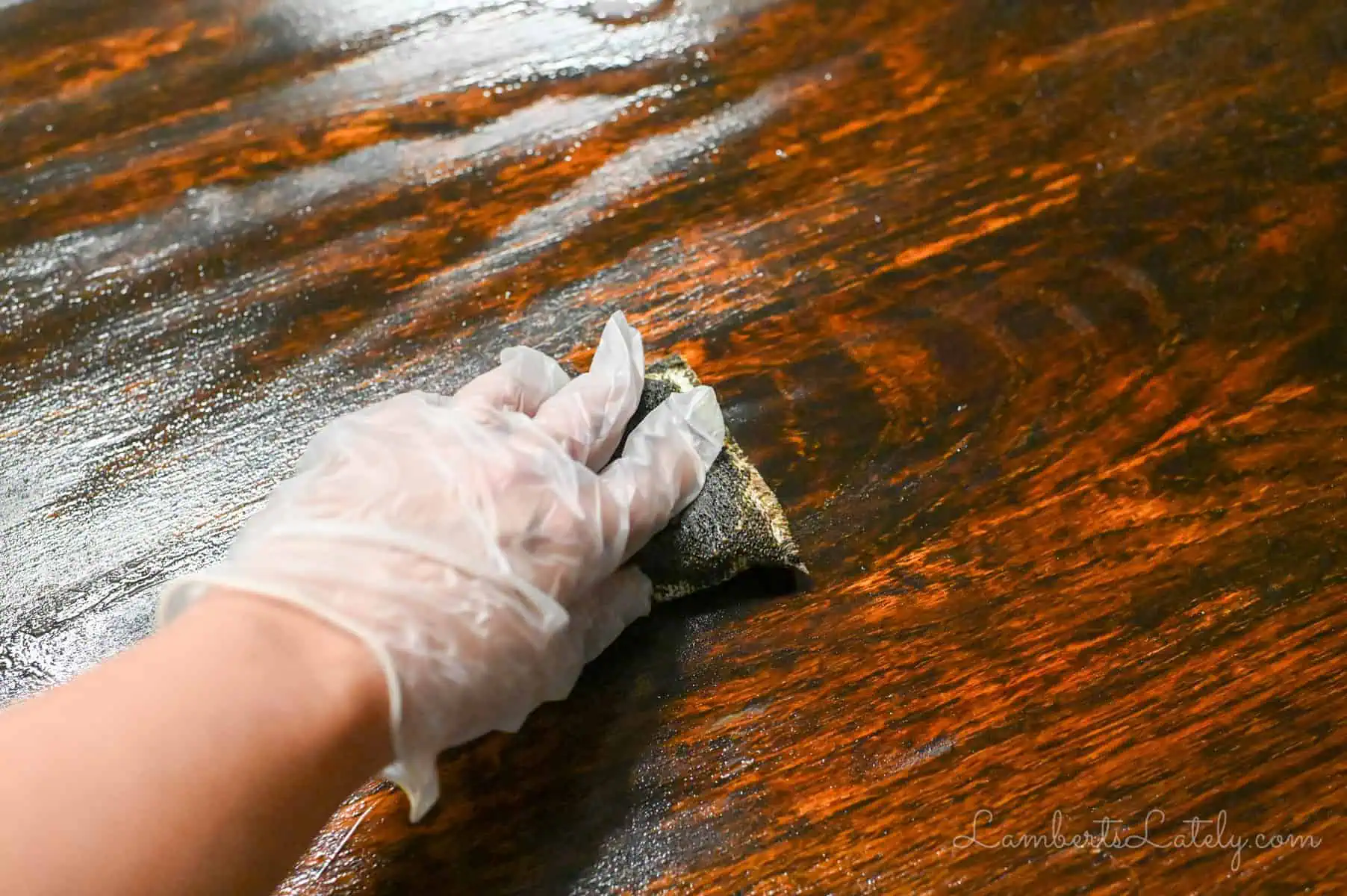 scrubbing a wood table with a scrub sponge.