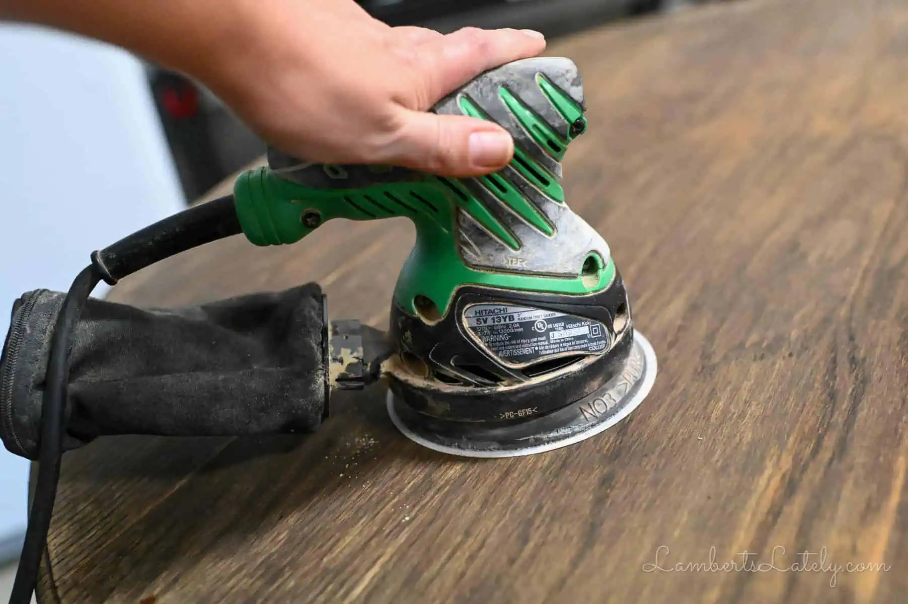 using an orbital sander on a table.