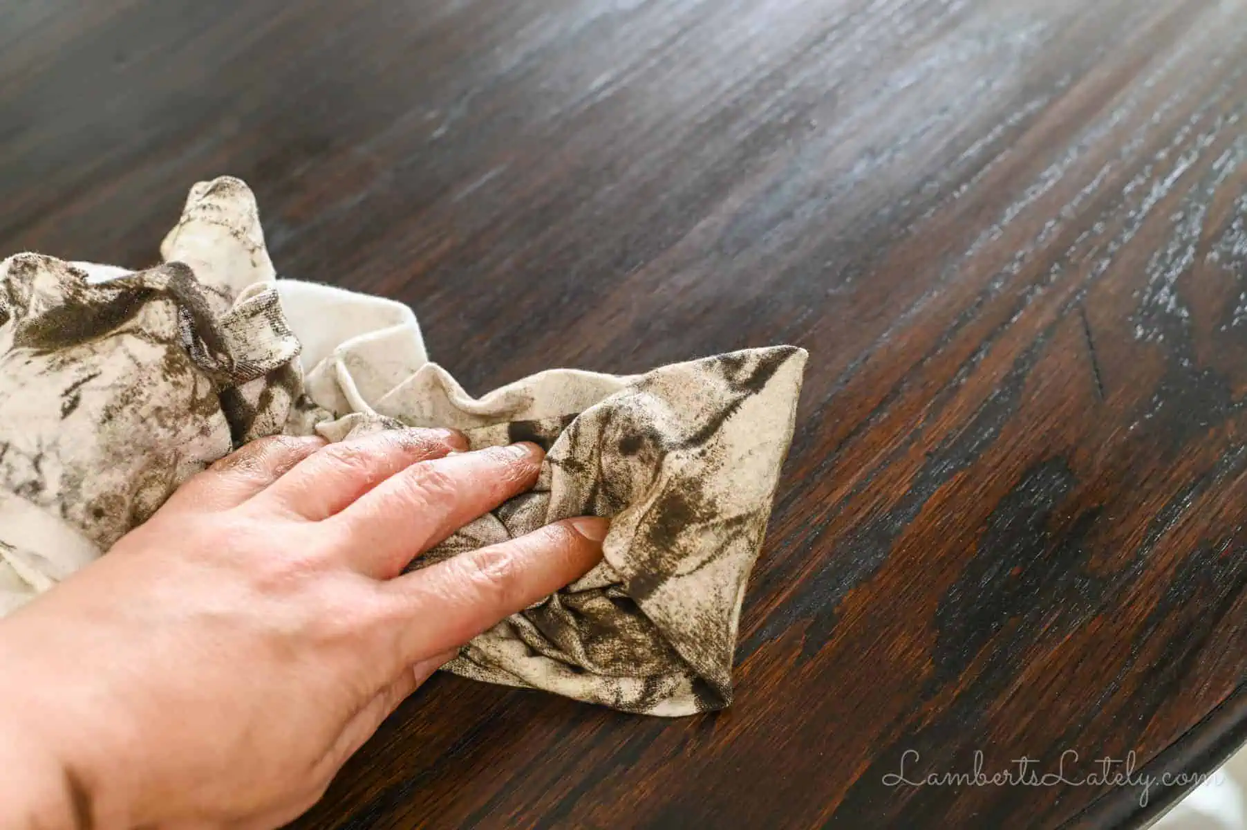 wiping stain off of a table with an old t-shirt.