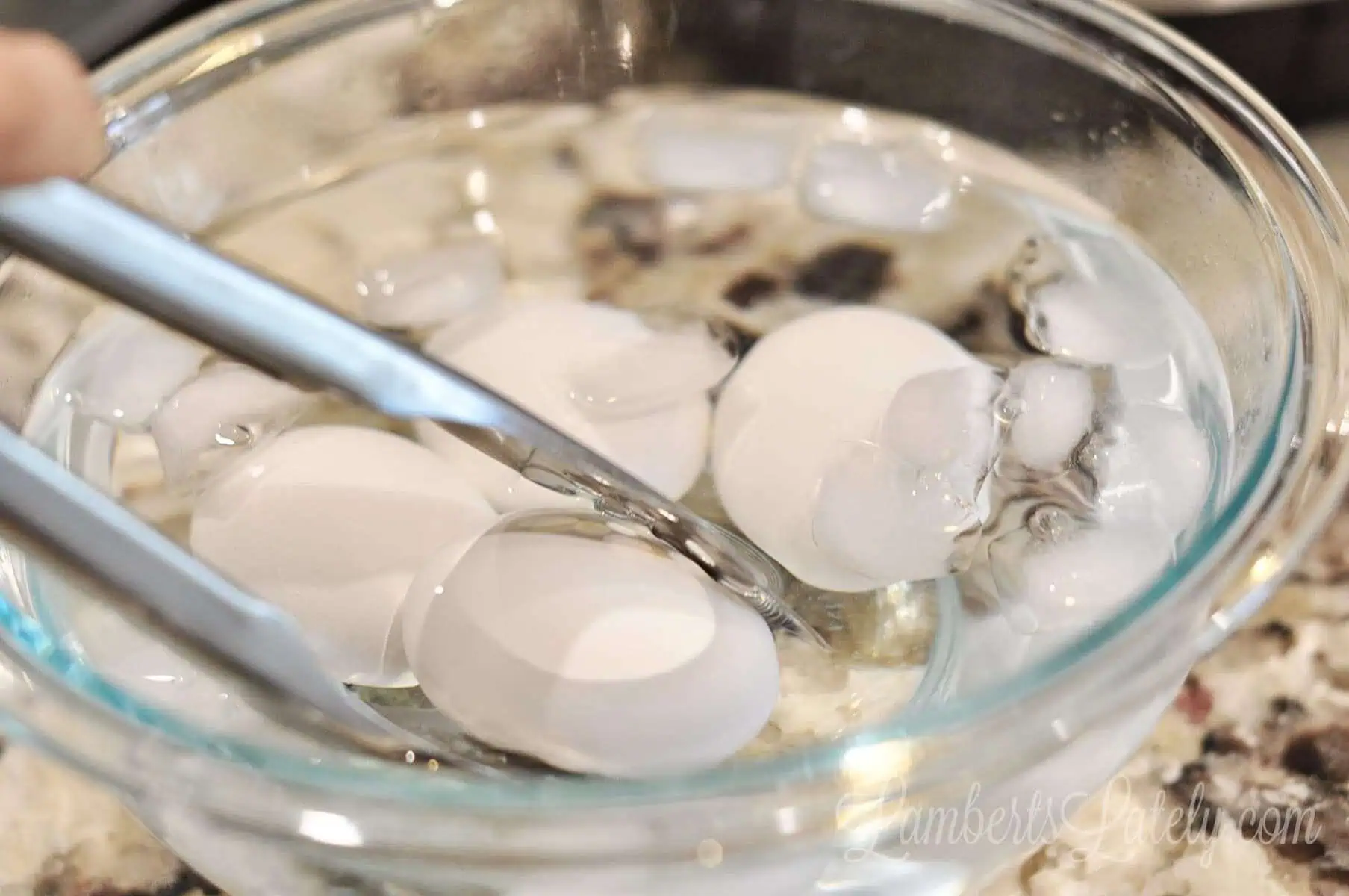 placing eggs in an ice bath with tongs.