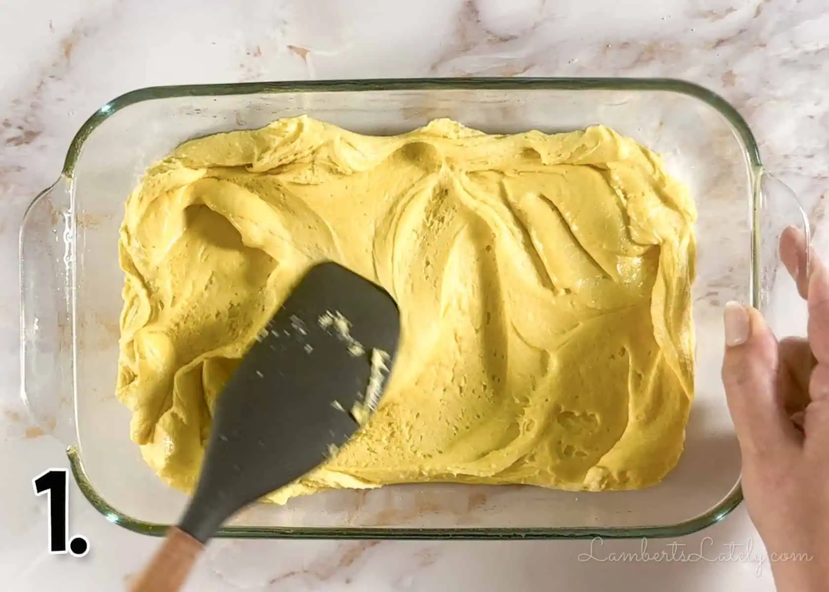 spreading brownie batter in a glass baking dish.