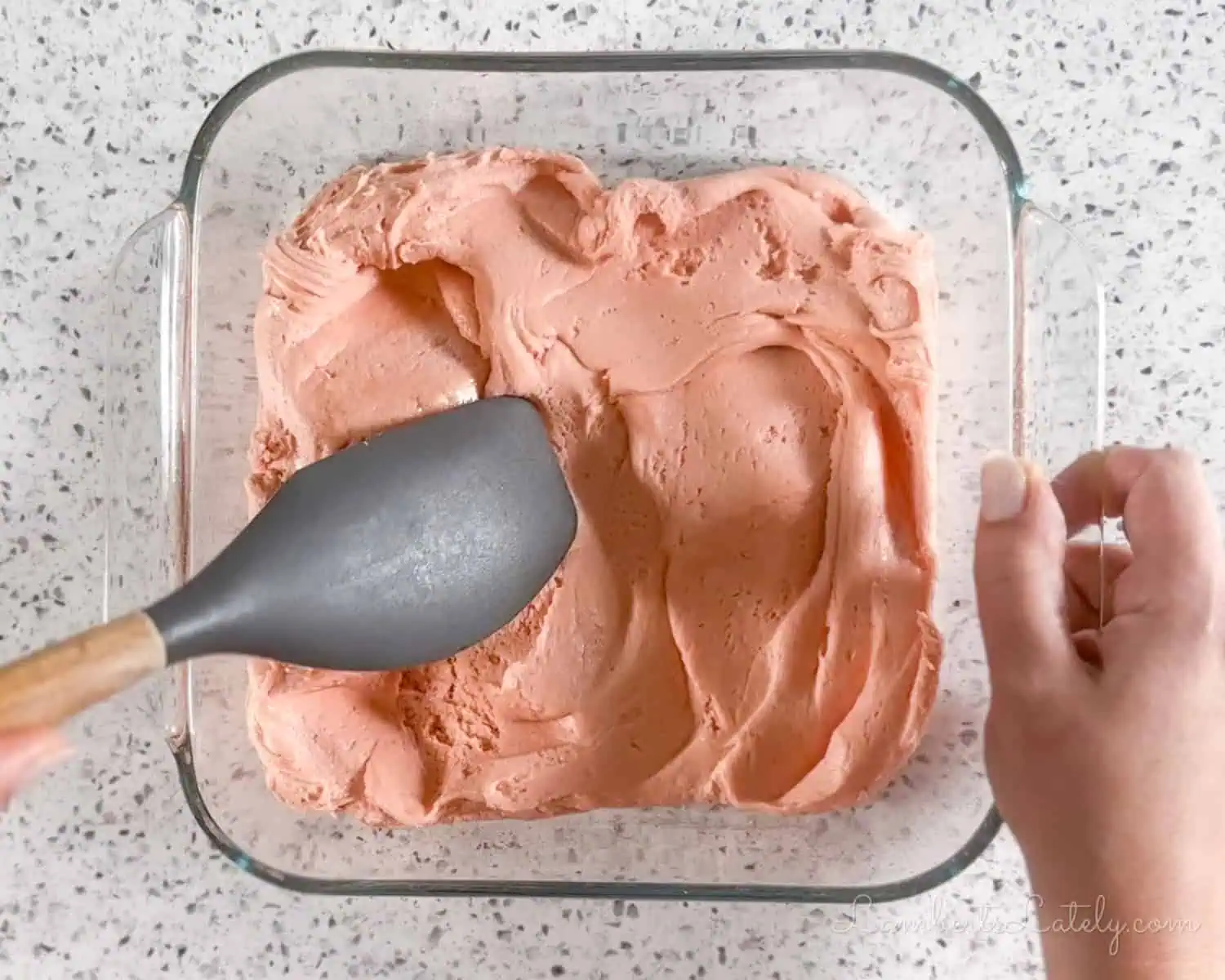 spreading brownie batter in a glass baking dish.
