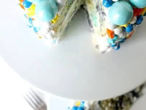 layer cake on a serving platter, topped with big sprinkles.