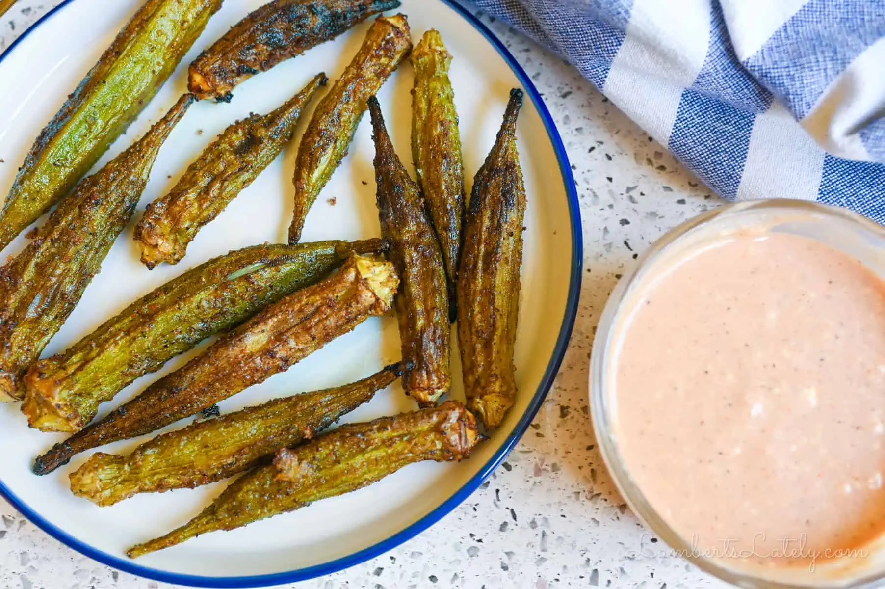 air fryer okra on a plate next to dipping sauce.