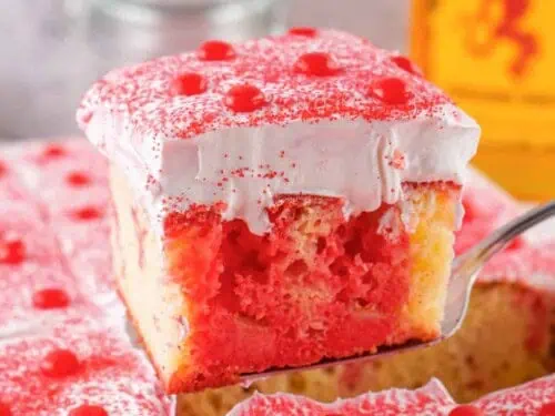holding a slice of fireball poke cake on a serving knife.