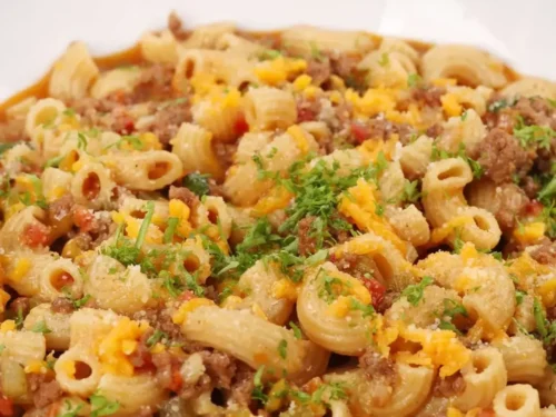 goulash in a bowl, sprinkling garnish over the top.
