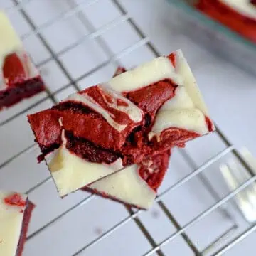 red velvet brownie with cream cheese swirl stacked on a baking rack.