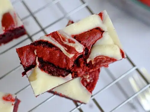 red velvet brownie with cream cheese swirl stacked on a baking rack.