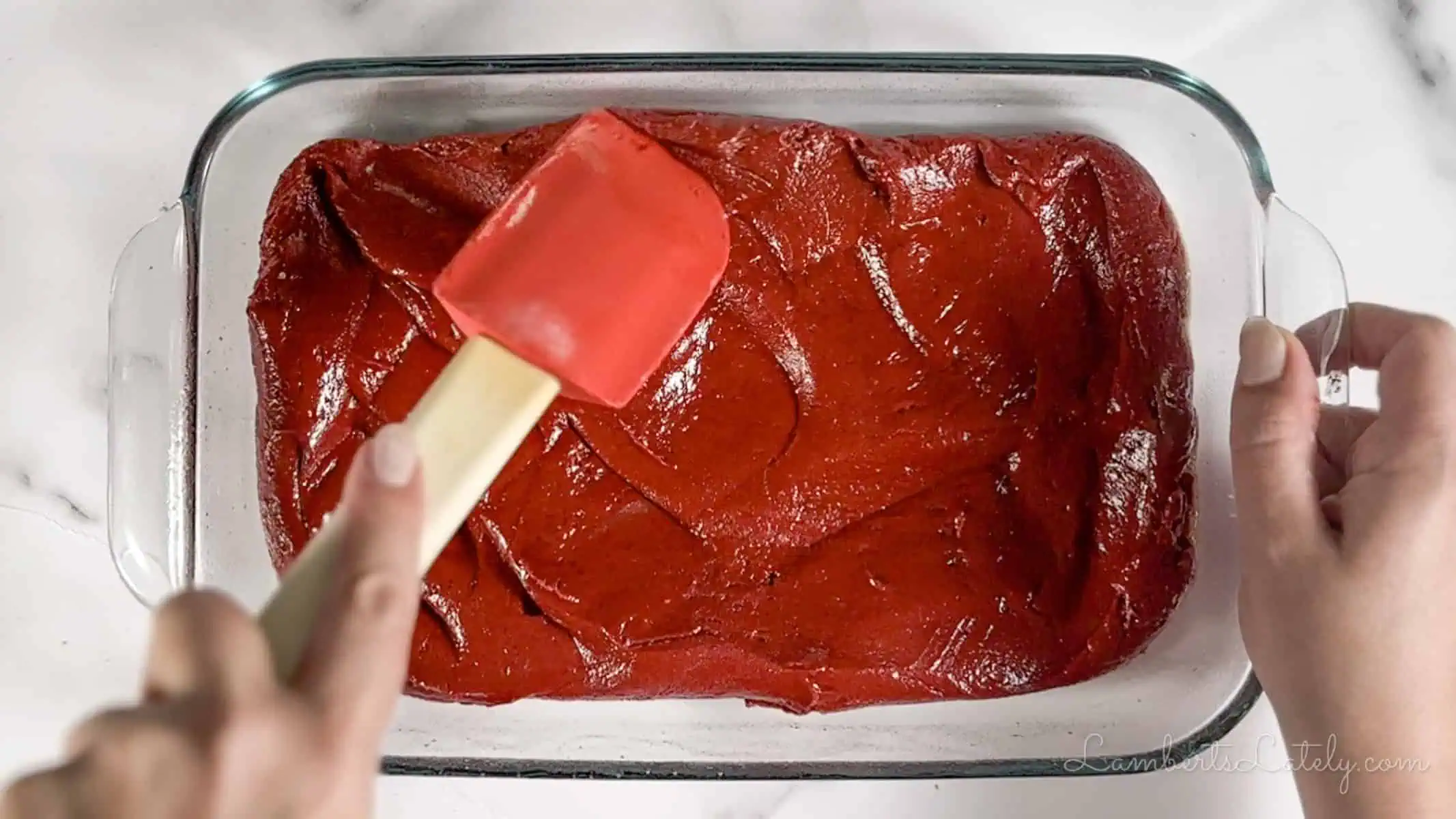 red velvet brownie batter spread in a baking dish.