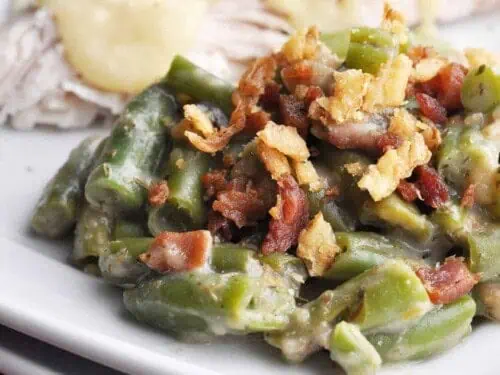 green bean casserole, covered in bacon pieces, on a plate.