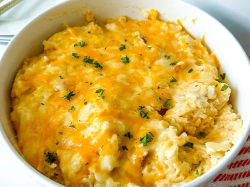 funeral potatoes covered with cheese in a bowl, over a cloth napkin.