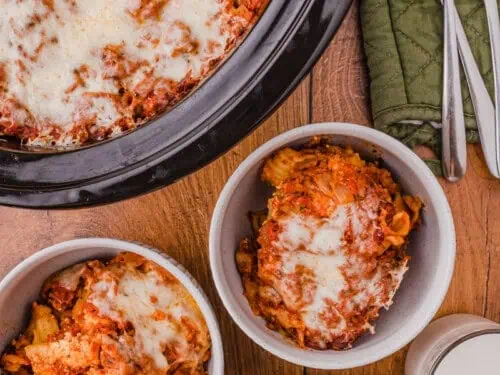 bowls of ziti next to a crock pot, with forks.