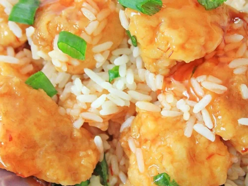 sweet and sour chicken covered in green onions, over rice.