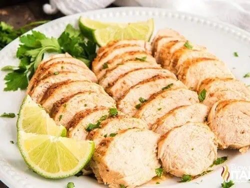 chicken breasts sliced on a platter, with limes.
