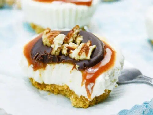 turtle cheesecake on a plate, surrounded by other servings.