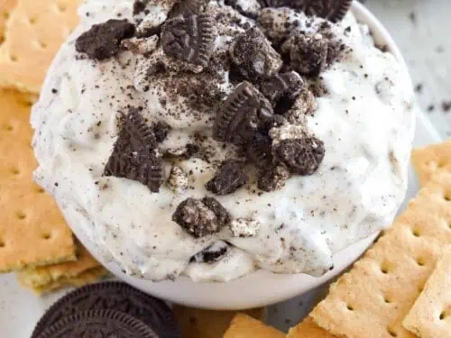 bowl of oreo fluff dip with cookie sticking out of top, with graham crackers next to bowl.