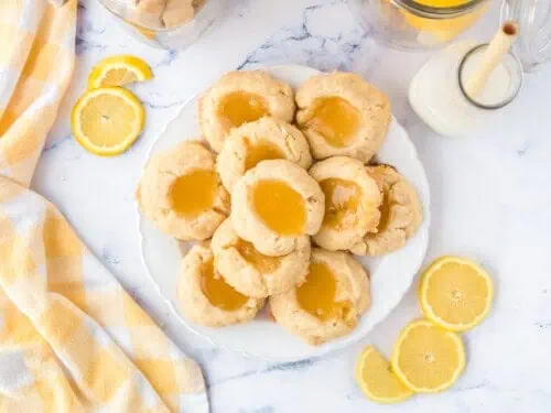 lemon curd thumbprint cookies on a plate, next to napkin.