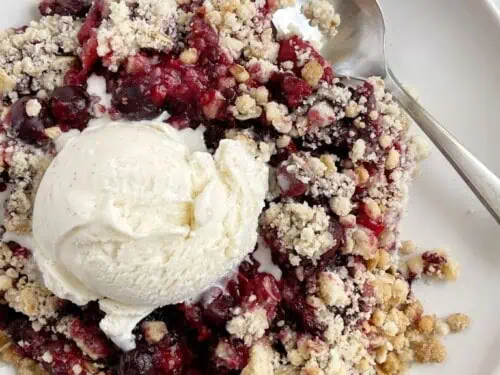 bowl of berry crisp dump cake with a spoon, topped with ice cream.