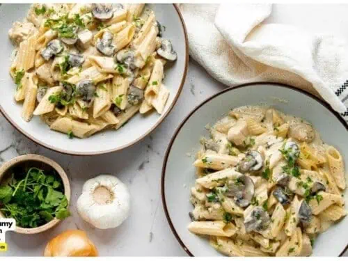 two bowls of mushroom and chicken pasta next to toppings, napkin.