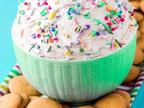funfetti cake batter dip in a bowl, topped with sprinkles, next to vanilla wafers.