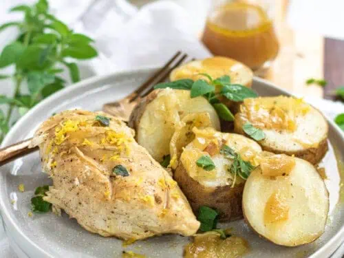 chicken and potatoes on a plate, covered with cheese.