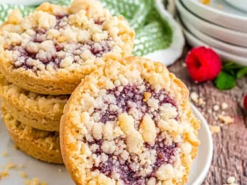 raspberry tart cookies stacked on a plate.