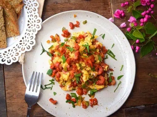 chorizo and eggs on a plate, with green herb garnish.