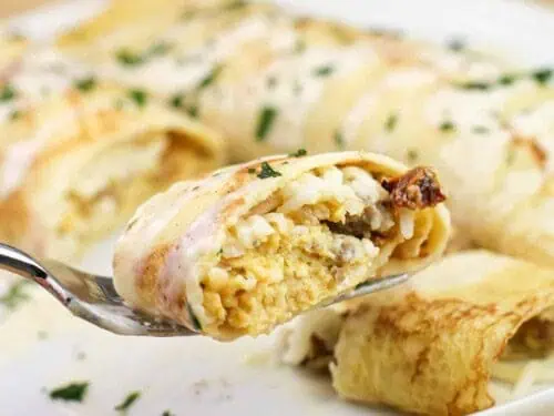 crepes filled with sausage and eggs, covered in cream sauce.