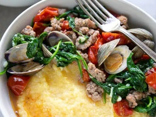 clams and sausage over polenta in a bowl.
