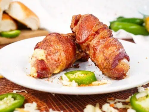 armadillo eggs wrapped in bacon, stacked on a plate.