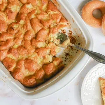 donut bread pudding in a casserole dish, with plate with a serving and donuts next to it.